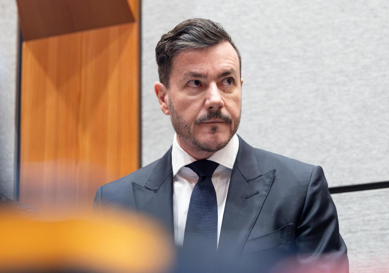 Mann in dunkelblauem Anzug vor hellem Hintergrund.