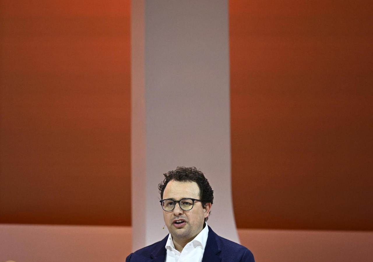 Dario Amodei spricht auf einer Bühne vor orangefarbenem Hintergrund.