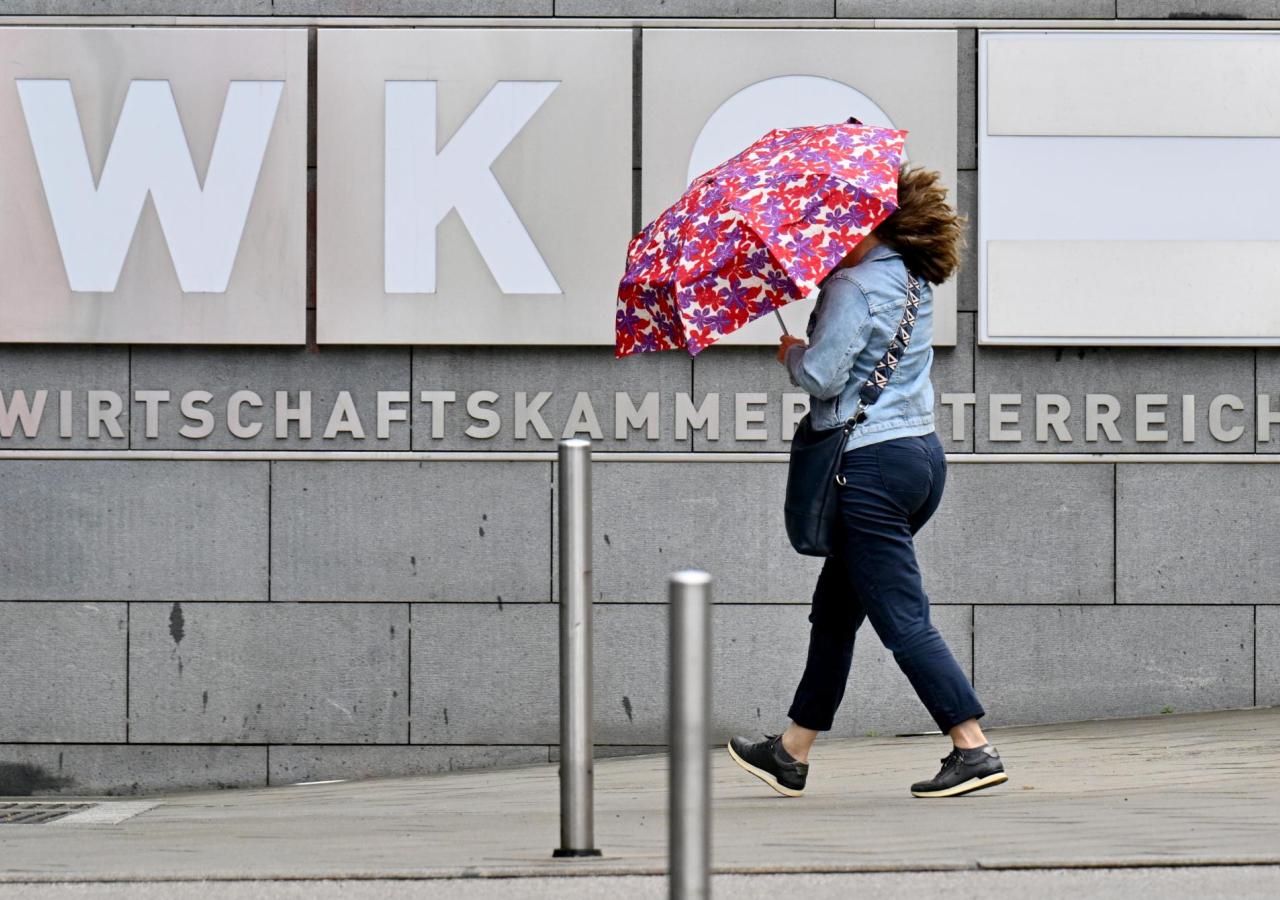 Frau mit Regenschirm vor dem Schild der WKO-Zentrale in Wien