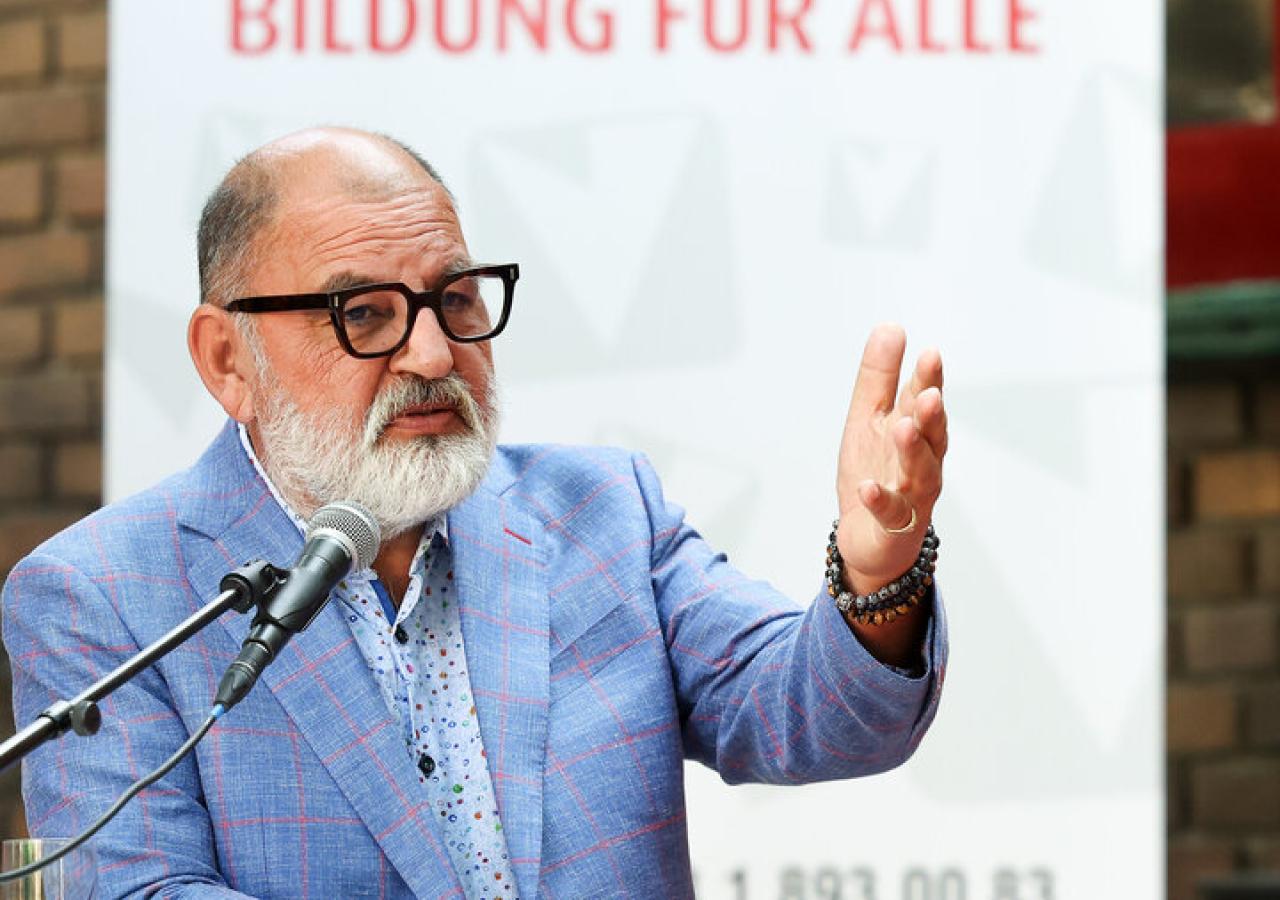 Herbert Schweiger vor einem Plakat der Volkshochschulen