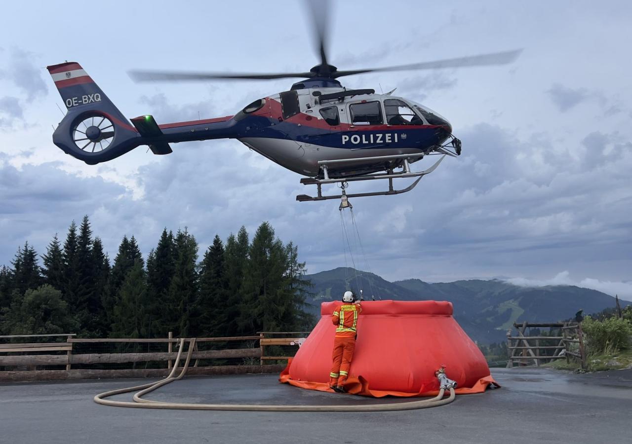 Ein Polizeihelikopter hovert über einem orangen Wasserbehälter.