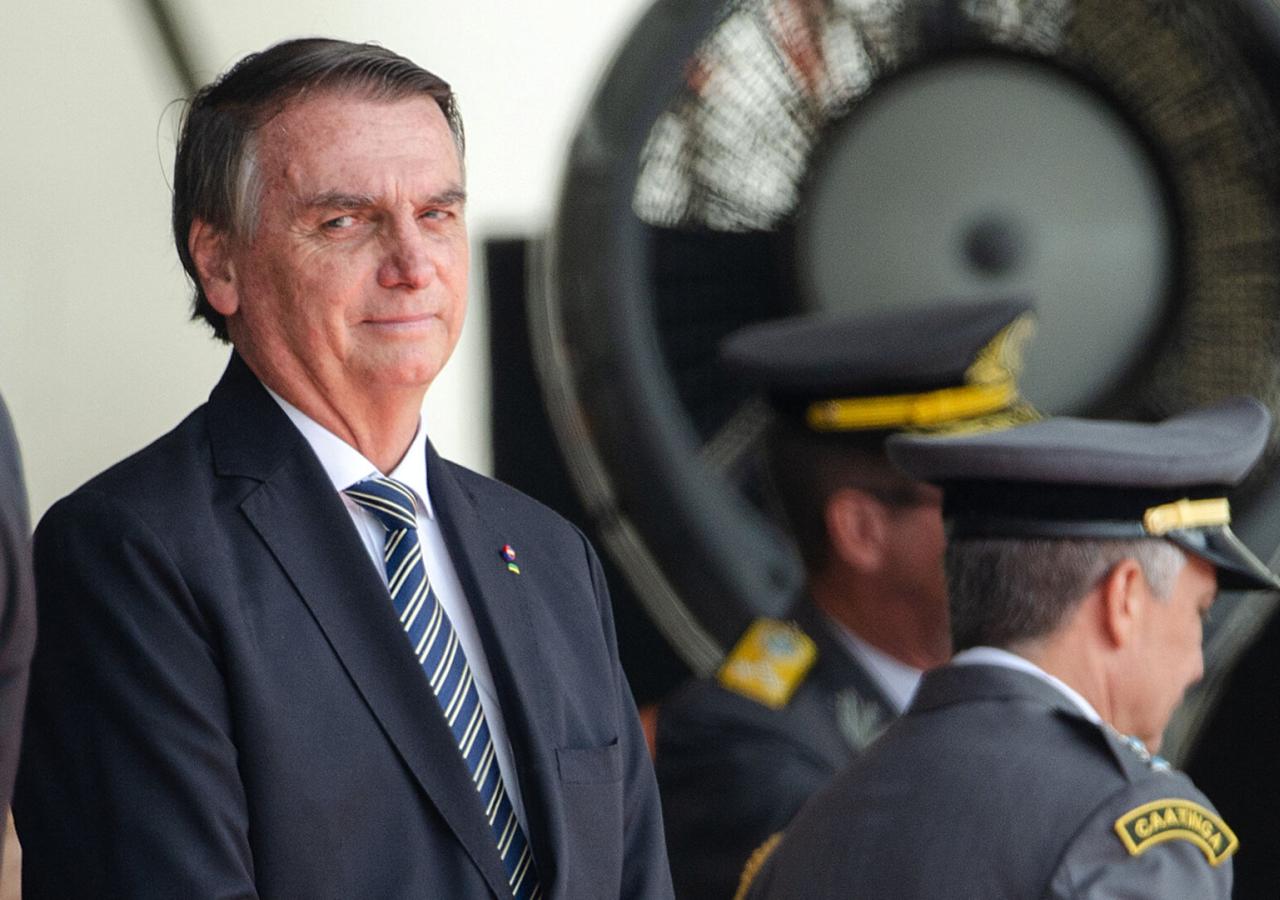 Jair Bolsonaro in Anzug vor zwei Polizeibeamten.