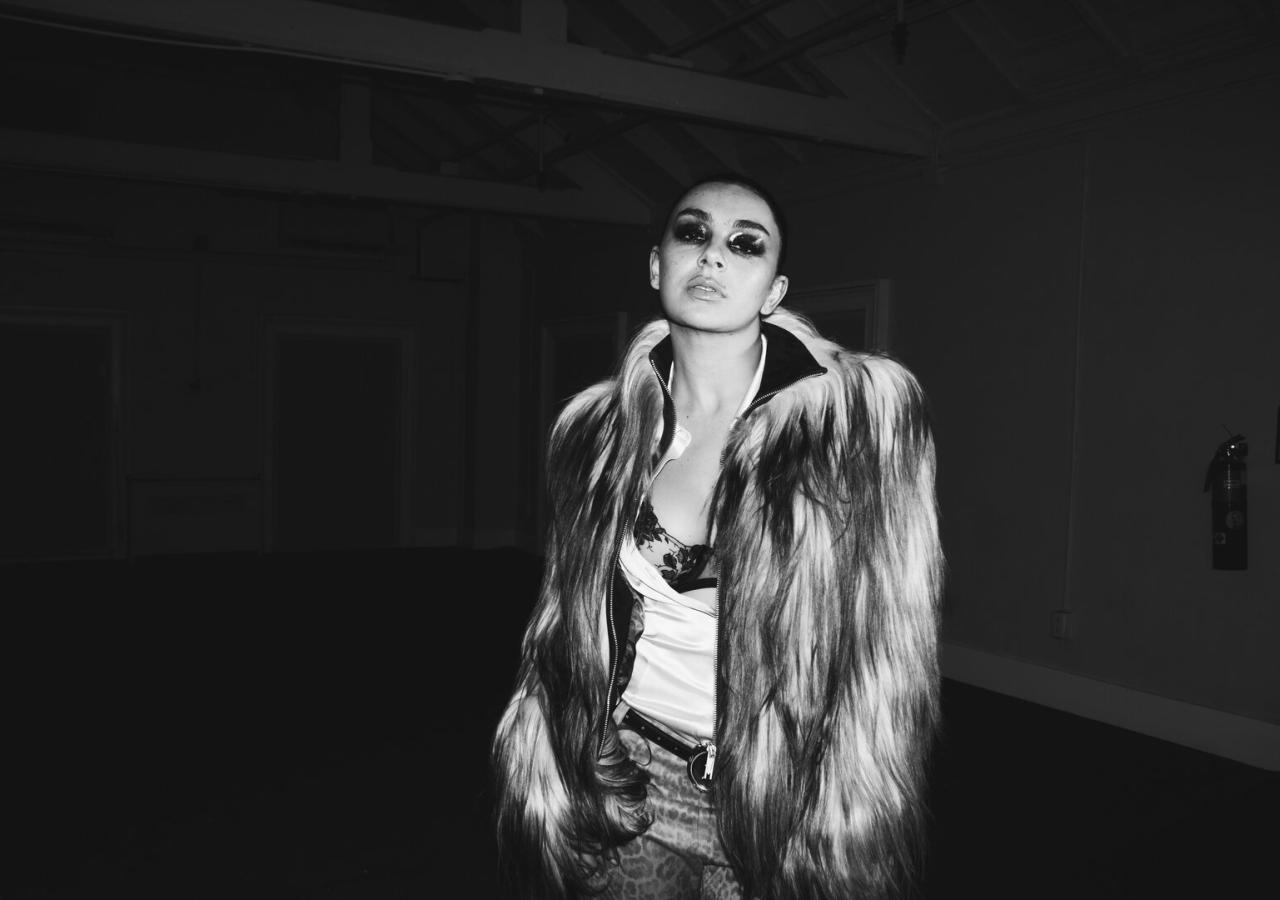 Die Musikerin Charli xcx in eienm schwarzweißen Foto, mit Sonnenbrillen und Pelzjacke