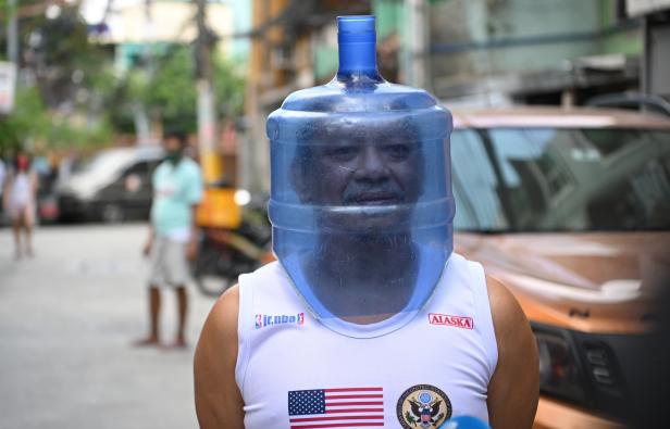 Ein Bewohner mit einem improvisierten Gesichtsschutz aus einem Wassertank aus Kunststoff in Manila. Ein Bewohner mit einem improvisierten Gesichtsschutz aus einem Wassertank aus Kunststoff in Manila.