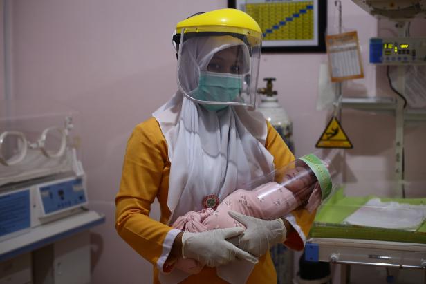 Eine indonesische Krankenschwester in Schutzkleidung hält ein Neugeborenes mit einem Gesichtsschutz als Schutzmaßnahme inmitten der COVID-19-Coronavirus-Pandemie in einer Klinik in Bireuen, Provinz Aceh. Eine indonesische Krankenschwester in Schutzkleidung hält ein Neugeborenes mit einem Gesichtsschutz als Schutzmaßnahme inmitten der COVID-19-Coronavirus-Pandemie in einer Klinik in Bireuen, Provinz Aceh.