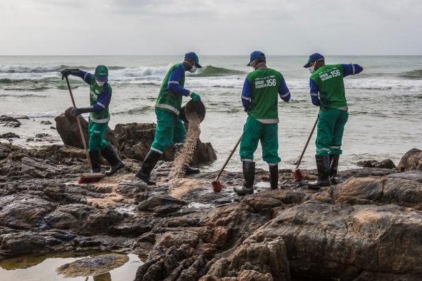 Kommunalarbeiter entfernen Rohöl am Strand von Pedra do Sal in Salvador im Bundesstaat Bahia, Brasilien.