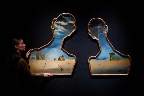 Eine Galerie-Assistentin posiert mit dem surrealistischen Kunstwerk von Salvador DalÌ ,"Couple aux títes de pleins nuages“ (Paar mit Köpfen voller Wolken), während des Verkaufs von Impressionisten und moderner Kunst im Bonhams-Auktionshaus im Zentrum von Eine Galerie-Assistentin posiert mit dem surrealistischen Kunstwerk von Salvador DalÌ ,"Couple aux títes de pleins nuages“ (Paar mit Köpfen voller Wolken), während des Verkaufs von Impressionisten und moderner Kunst im Bonhams-Auktionshaus im Zentrum von