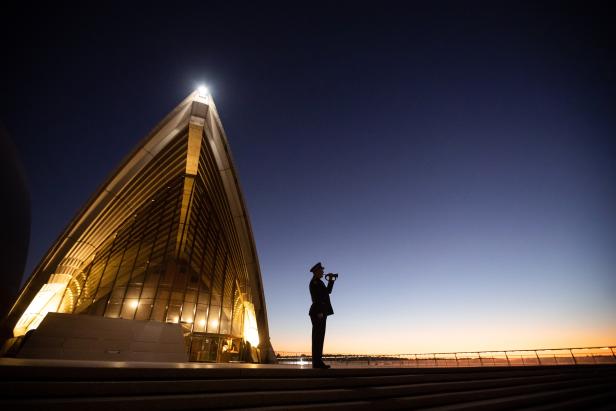 Das Bild zeigt einen einsamen Trompeter, der "The Last Post" auf den Stufen des Sydney Opera House spielt. Das Bild zeigt einen einsamen Trompeter, der "The Last Post" auf den Stufen des Sydney Opera House spielt.