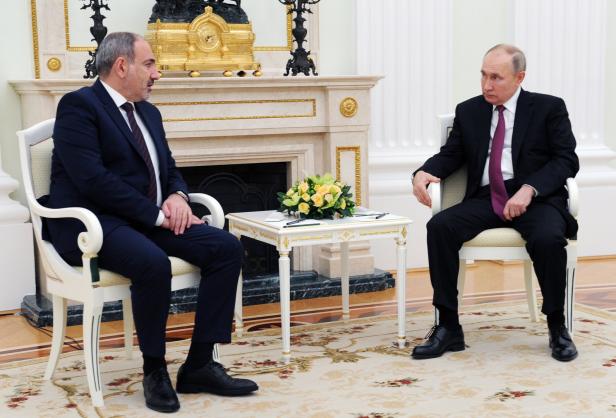 Wladimir Putin trifft sich mit einem Mann in einem formellen Rahmen.