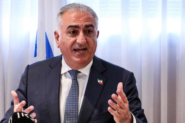 Reza Pahlavi spricht vor einer Flagge.