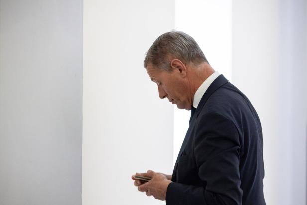 Ein Mann im Anzug (Christian Pilnacek) schaut auf sein Mobiltelefon.