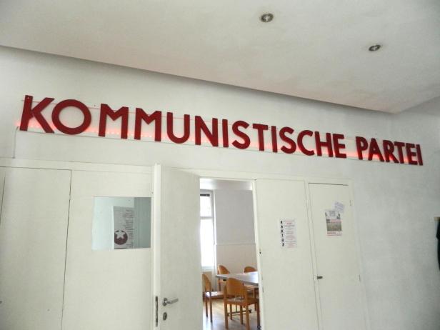 Roter Schriftzug "Kommunistische Partei" vor roten LEDs in der Küche der KPÖ.