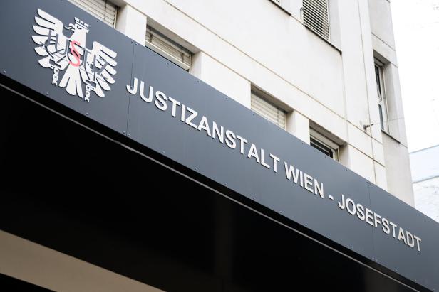Schriftzug „Justizanstalt Wien - Josefstadt“ und ein stilisierter Adler an einer Gebäudefassade.