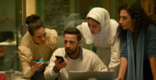 Gaza-Dokudrama der zwiespätigen Art: Szene aus "The Voice of Hind Rajab" Drei Frauen stehen um einen sitzenden Mann, der auf ein Mobiltelefon blickt.