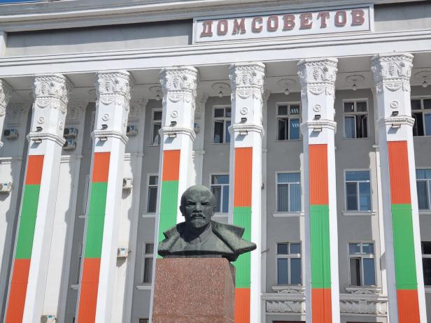 Eine Lenin-Statue steht vor einem weißen Haus, darüber die Aufschrift "Dom Sovjetov".
