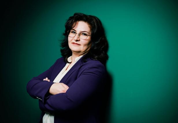 Fatma Akay-Türker lehnt an einer grünen Wand