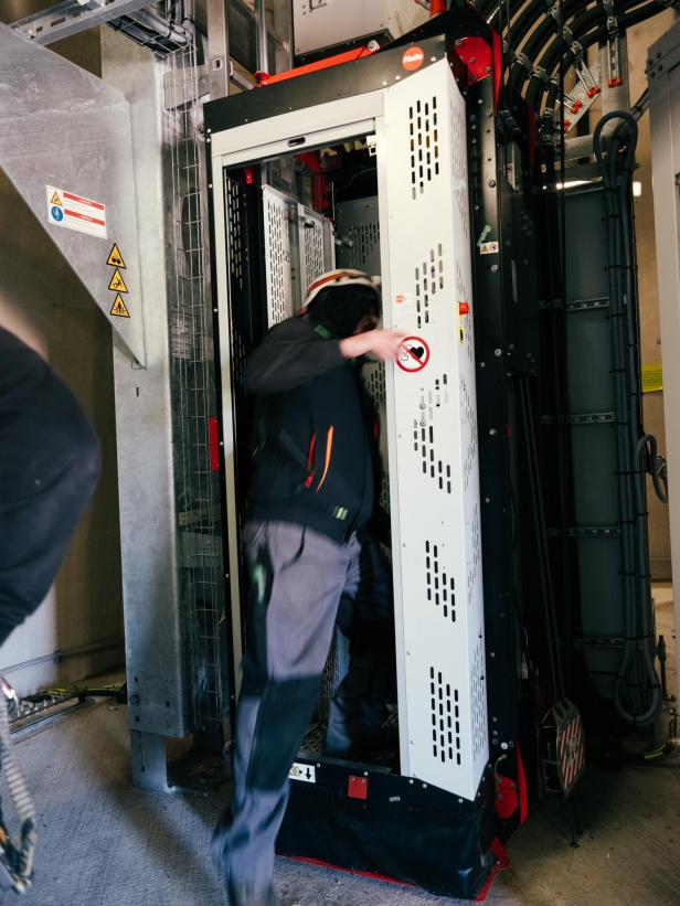 zu sehen ist ein Techniker, der in einen Materiallift innerhalb eines Windrades steigt