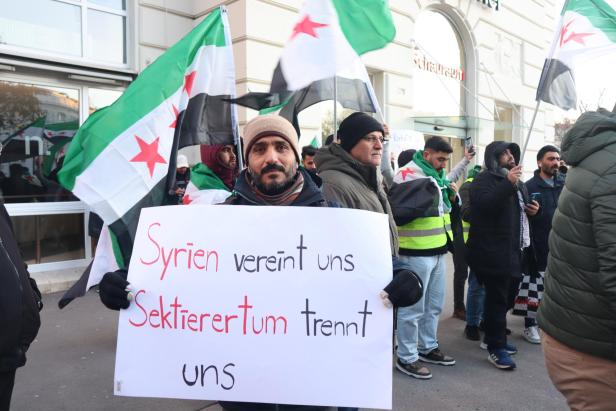 Ein Mann hält ein Schild mit der Aufschrift "Syrien vereint uns  Sektierertum trennt uns" hoch.