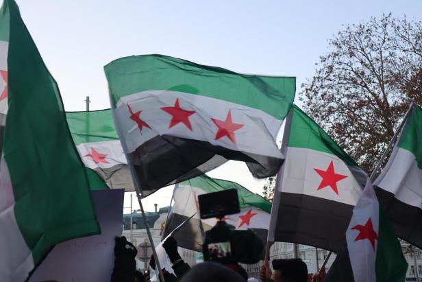 Syrische Flaggen (grün, weiß, schwarz - in der Mitte drei rote Sterne) werden auf einer Demo geschwenkt.