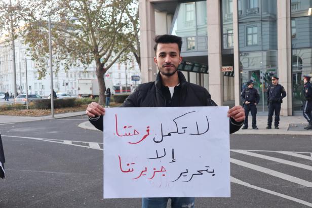 Ein Mann hält ein Schild mit arabischer Aufschrift hoch.