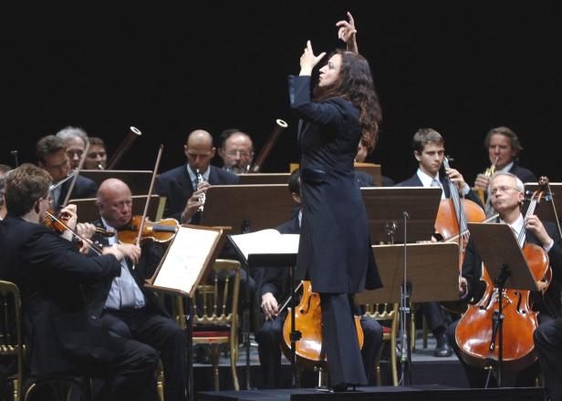 Junge Dirigentin in Aktion, vor einem fast durchwegs männlich besetzten Orchester
