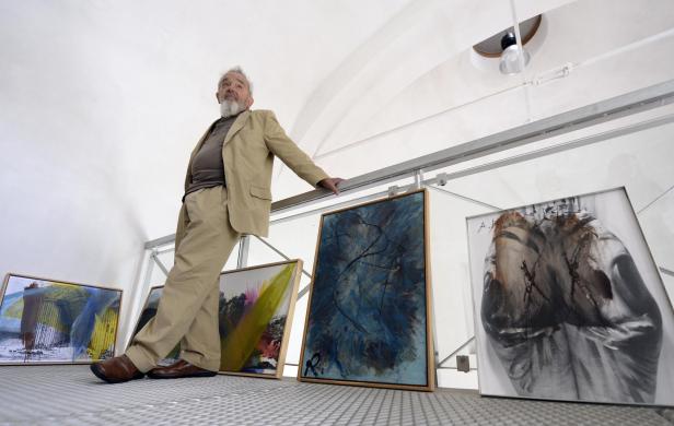Arnulf Rainer vor einigen seiner noch am Boden lehnenden Werke, aus der Untersicht fotografiert