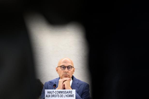 Volker Türk sitzt hinter einem Umriss, er stützt seinen Kopf auf seine Hände.
