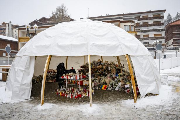 Kerzen und Blumen in einem vor Schnee schützenden Zelt vor dem Club in Crans Montana. 