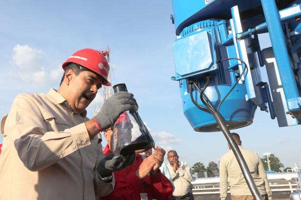 Maduro mit Helm, er betrachtet eine Ölprobe in einem Glaskrug