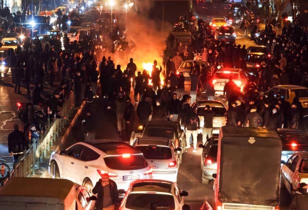 Nachtaufnahme von einer Straße voller stehender Autos und Menschen