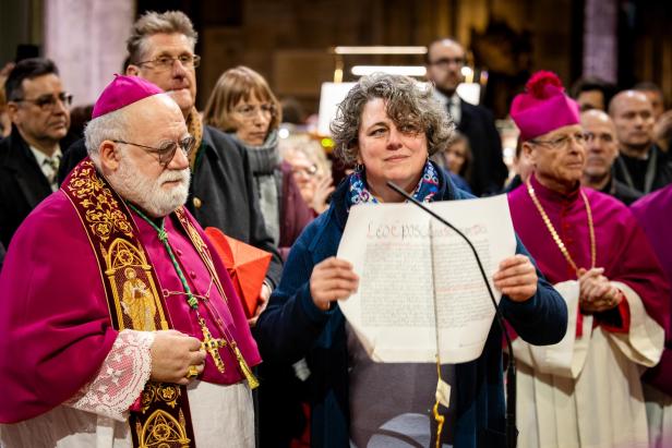 Eine Frau hält in einer Kirche eine Urkunde 