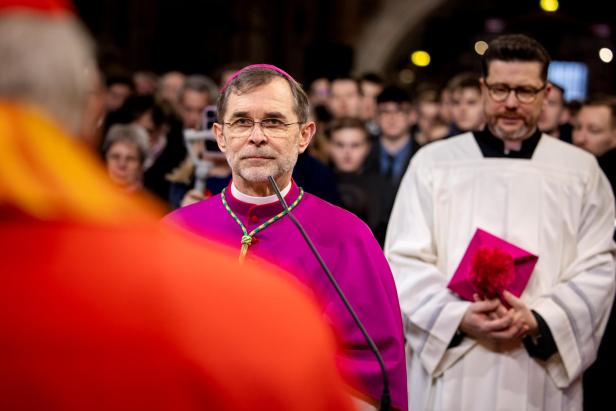 Josef Grünwidl steht im Ornat während seiner feierlichen Amtseinführung als neuer Erzbischof von Wien im Stephansdom, umgeben von Geistlichen und Gläubigen.