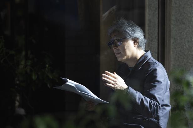 Der Filmemacher Park Chan-wook in einem halbdunklen Raum, mit ein paar Zetteln in der Hand