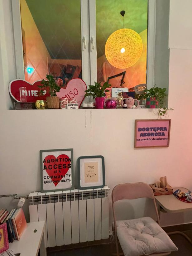 Regal mit Abotak-Merchandise, Abtreibungspillen und Plakat einer älteren Frau an der Wand.