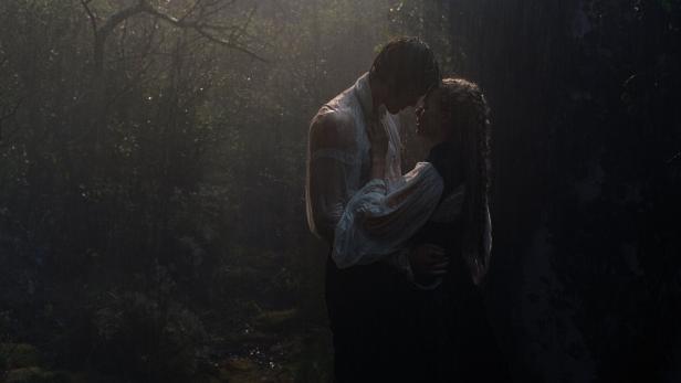 Das Schauspiel-Duo Jacob Elordi und Margot Robbie in dunklem Raum, einander küssend