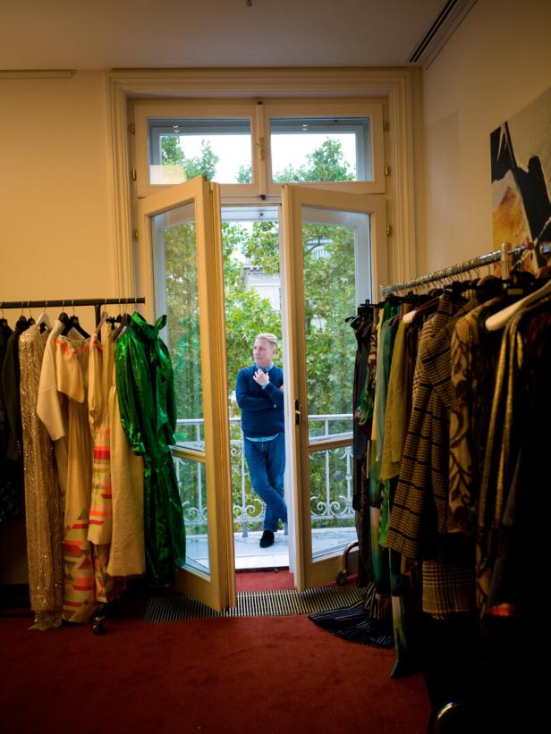 Modedesigner Atil Kutoglu steht hinter einer geöffneten Balkontüre auf dem Balkon