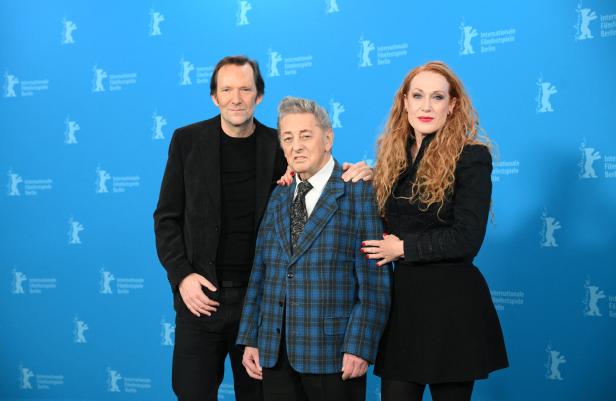 Der Wiener Musiker Al Cook, vor blauer Wand flankiert von dem Regie-Duo Tizza Covi und Rainer Frimmel