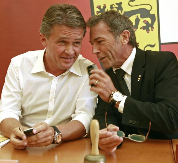 Zwei Männer, Peter Westenthaler und Jörg Haider, sitzen nebeneinander, einer flüstert dem anderen etwas ins Ohr, beide wirken konzentriert und freundlich.