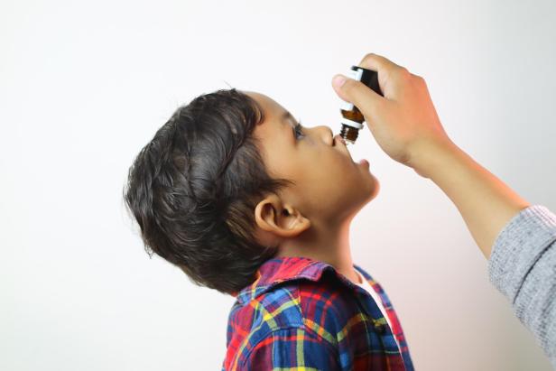 Ein Kind nimmt ein homöopathisches Präparat ein.