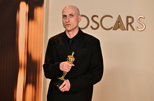 Der Musiker und Komponist Daniel Blumberg, 35, hält mit ernstem Blick einen Oscar