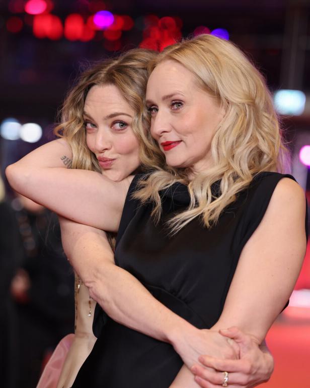 Die Schauspielerin Amanda Seyfried umarmt die Regisseurin Mona Fastvold, hinter ihnen blinken unscharf Lichter auf.