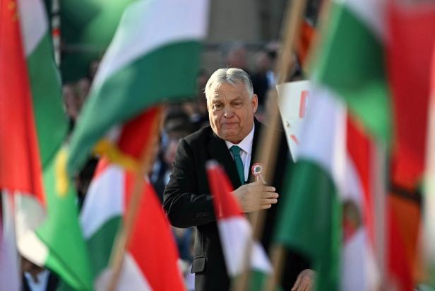 Viktor Orban steht vor Menschen die ungarische Flaggen schwenken.