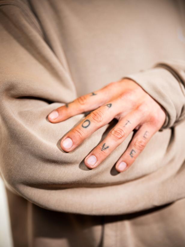 Hand mit Tattoos auf den Fingern