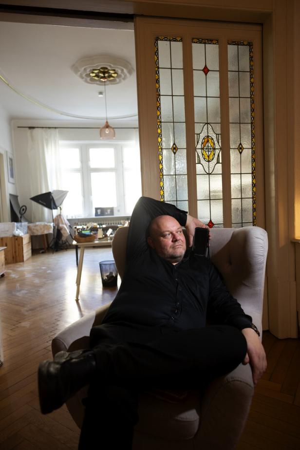 Der Filmemacher Michal Kosakowski sitzt in einem Lehnstuhl in einer Altbauwohnung