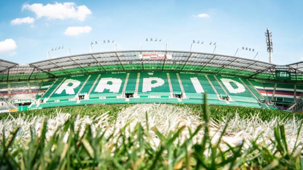 Blick über das Spielfeld auf die Tribüne eines Stadions mit der Aufschrift RAPID in großen Buchstaben