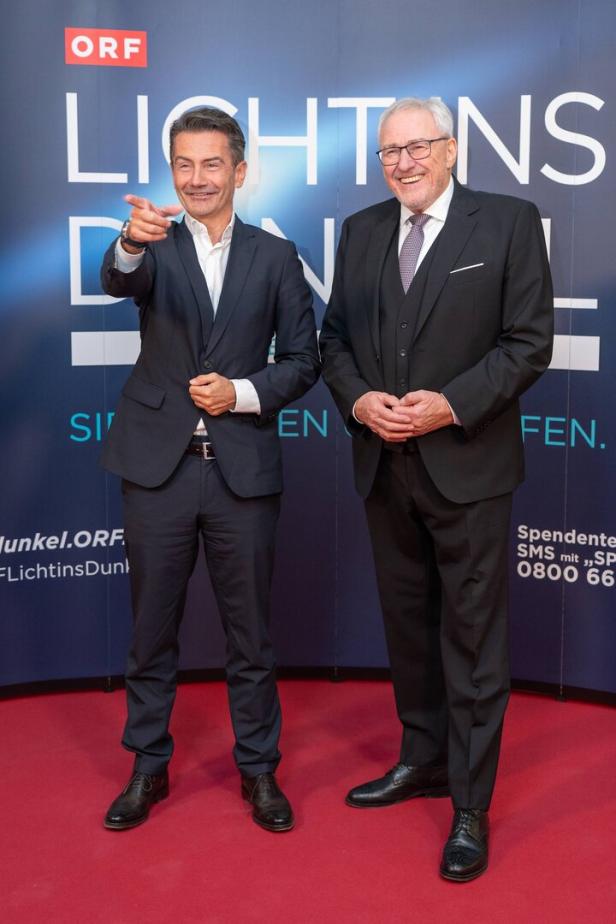 Zwei Männer in Anzügen - Roland Weißmann und Pius Strobl - posieren vor einem ORF-Hintergrund für "Licht ins Dunkel".