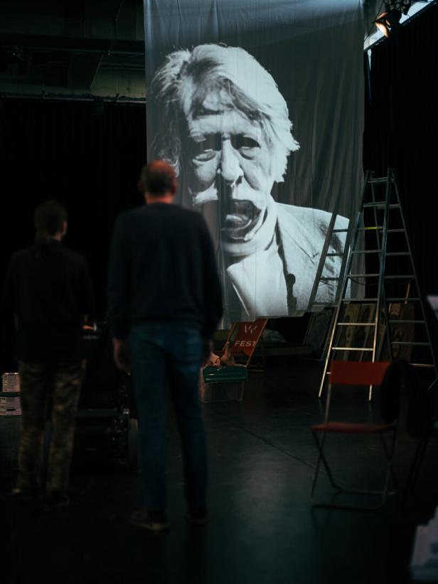 Ein schwarzweißes, KI-generiertes Bild des Theatermachers George Tabori, an eine Wand projiziert