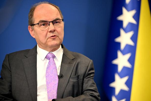 Der Hohe Repräsentant für Bosnien Christian Schmidt sitzt vor einer Bosnien-Flagge.