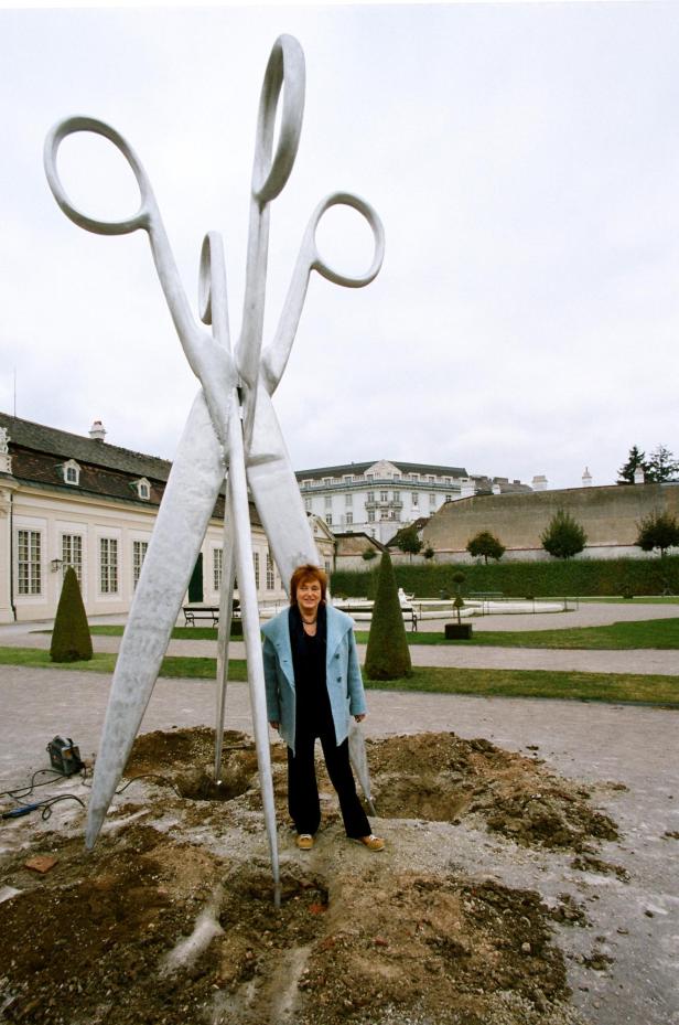 VALIE EXPORT 2010 vor einer Skulptur, die in Form einer doppelten, meterhohen Schere im Garten des Wiener Belvedere Platz fand.