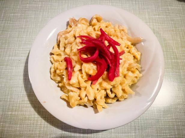 Das Bild zeigt Käsespätzle mit eingelegten Zwiebel und Kraut